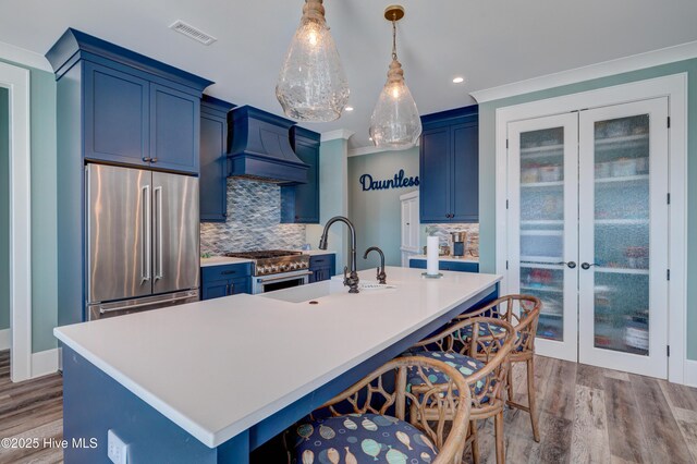 kitchen featuring stainless steel appliances, light countertops, light wood-type flooring, custom exhaust hood, and tasteful backsplash