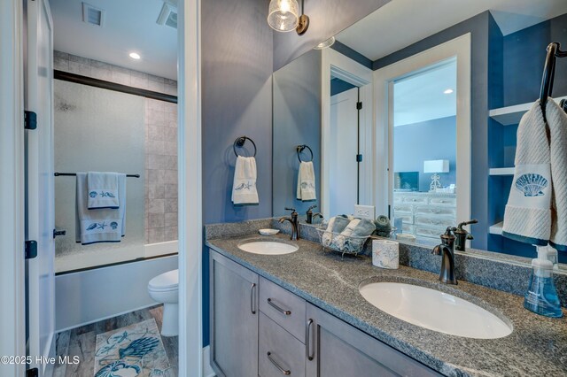 bathroom with toilet and bath / shower combo with glass door