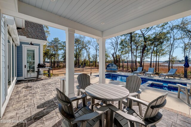 view of patio / terrace with an in ground hot tub, a fenced backyard, a fenced in pool, and outdoor dining space