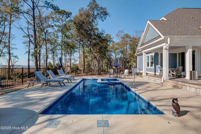 view of swimming pool with a pool with connected hot tub, a patio, and fence