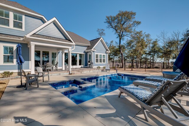 view of pool with a patio, fence, a fenced in pool, and an in ground hot tub