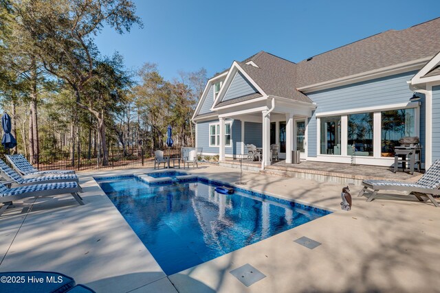 view of swimming pool with a patio area, a pool with connected hot tub, and fence