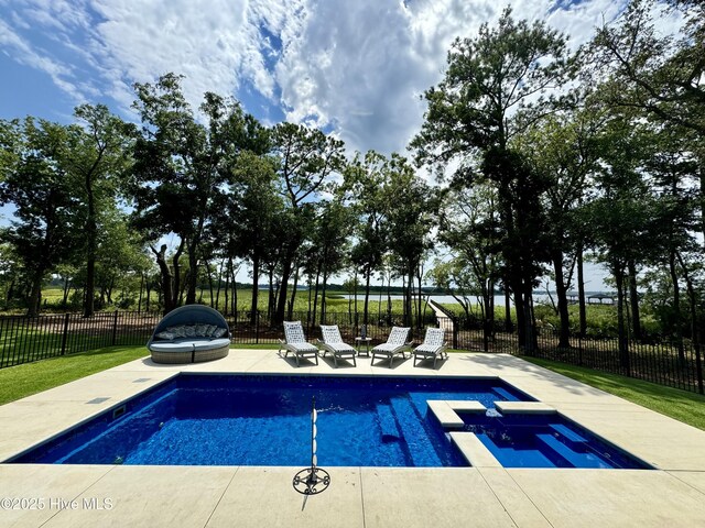 pool at dusk featuring a pool with connected hot tub, a patio area, and fence