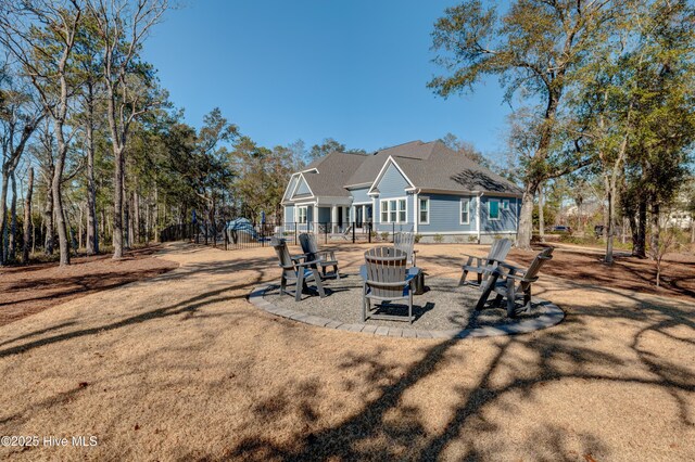 rear view of property with a yard, an outdoor fire pit, a patio area, and fence