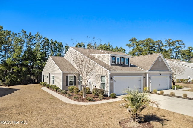 view of front of house with driveway, a front lawn, roof with shingles, and an attached garage