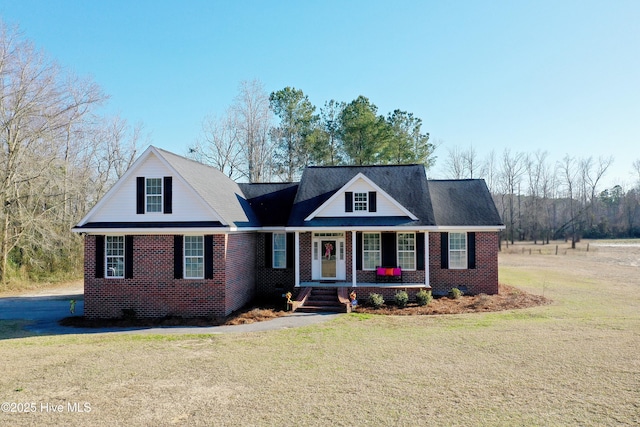 view of front of house with brick siding, a porch, and a front yard