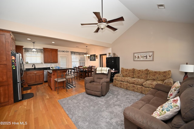 living room with vaulted ceiling, light wood-style flooring, visible vents, and a ceiling fan