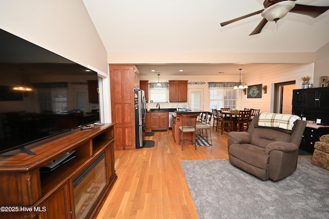 living room featuring light wood-style floors, vaulted ceiling, and a ceiling fan