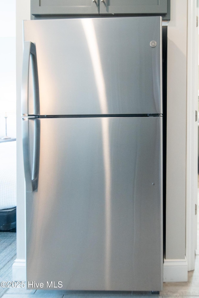 interior details featuring light wood-type flooring, freestanding refrigerator, and gray cabinetry