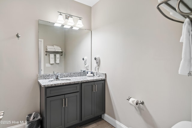 bathroom featuring baseboards, wood finished floors, and vanity