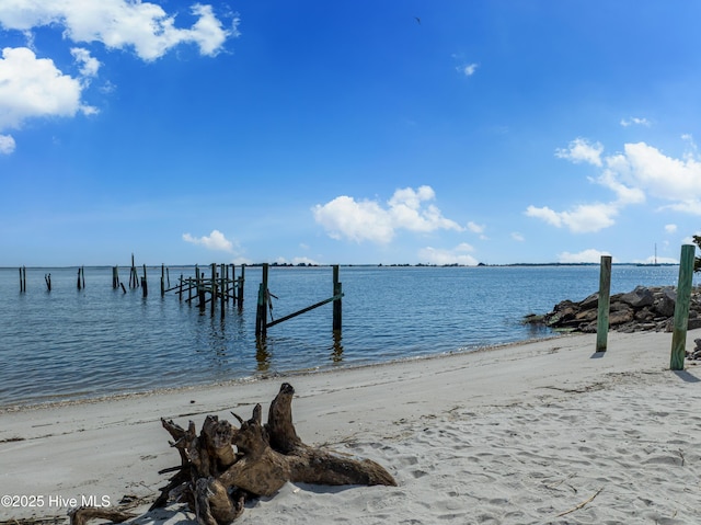 view of dock with a beach view and a water view