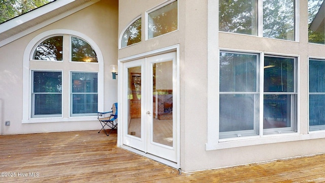property entrance featuring a deck, stucco siding, and french doors