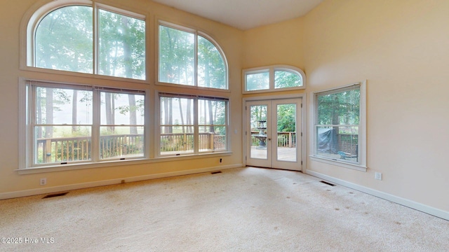 carpeted empty room with baseboards, visible vents, and french doors