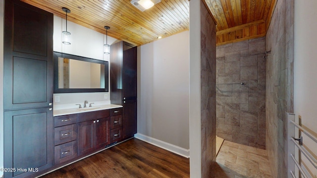 bathroom featuring wooden ceiling, baseboards, wood finished floors, vanity, and tiled shower