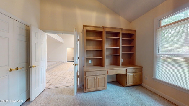 unfurnished office featuring baseboards, built in study area, vaulted ceiling, and light carpet