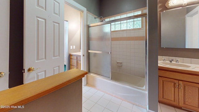 bathroom featuring combined bath / shower with glass door, vanity, and tile patterned flooring