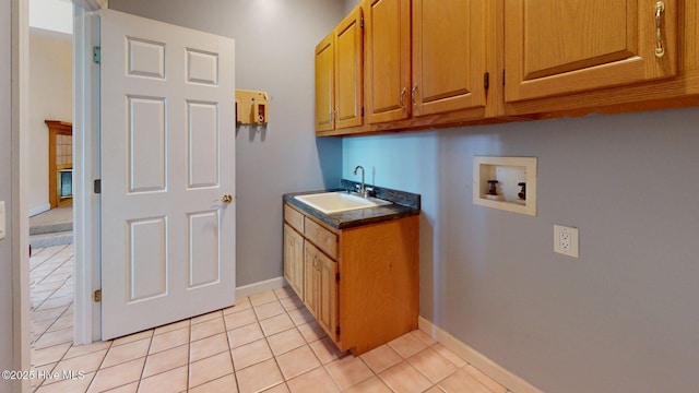 laundry room featuring a sink, cabinet space, light tile patterned floors, hookup for a washing machine, and baseboards