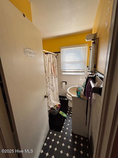 full bath featuring tile walls, toilet, wainscoting, vanity, and tile patterned floors