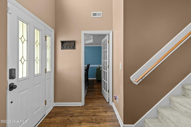 entryway featuring wood finished floors, visible vents, baseboards, and stairs