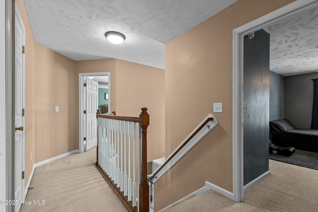 hall featuring baseboards, carpet flooring, and an upstairs landing