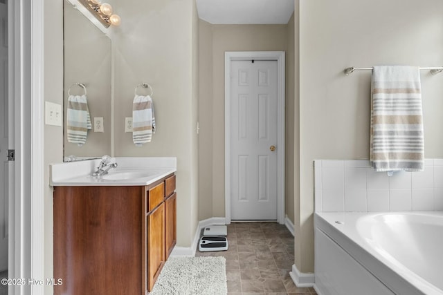 full bathroom featuring tile patterned floors, vanity, baseboards, and a bath