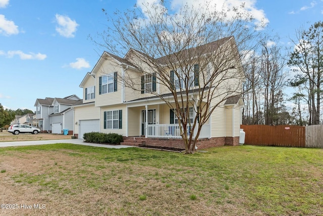 traditional home featuring covered porch, concrete driveway, fence, a garage, and a front lawn