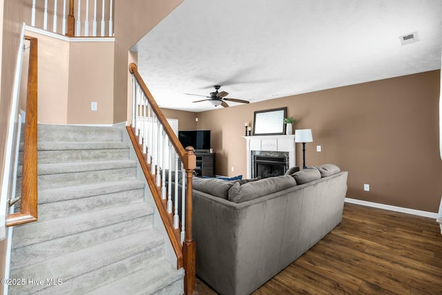 living area with baseboards, ceiling fan, stairway, dark wood-style flooring, and a high end fireplace