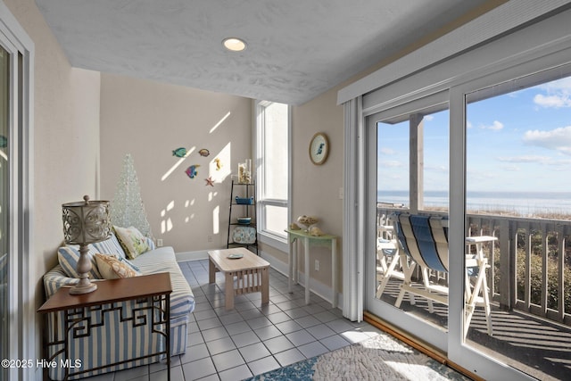 interior space featuring light tile patterned floors, a water view, and baseboards