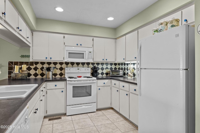 kitchen with dark countertops, visible vents, backsplash, white cabinets, and white appliances