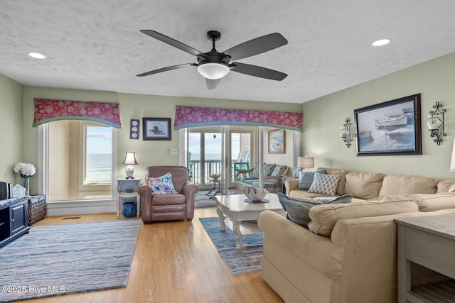 living room featuring recessed lighting, ceiling fan, a textured ceiling, and light wood finished floors