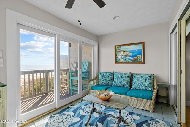 tiled living room with a water view and a ceiling fan