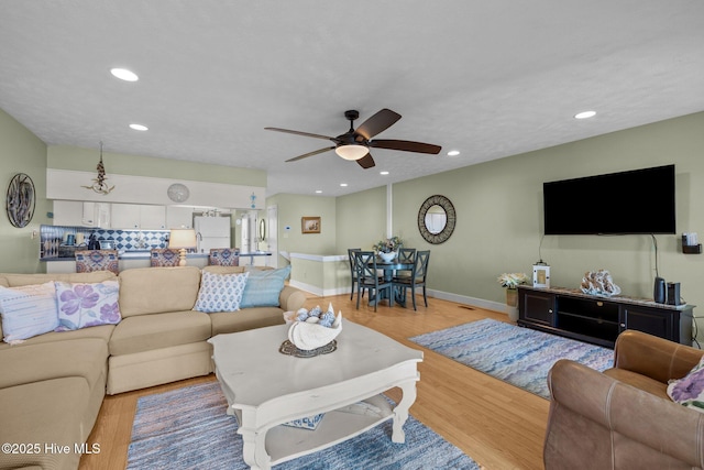 living room featuring light wood-type flooring, a ceiling fan, and recessed lighting