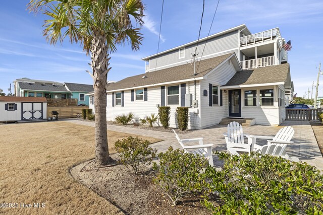 view of front of house featuring an outbuilding, a patio, fence, and a storage unit