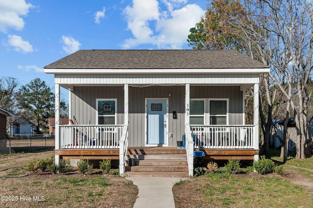 bungalow-style house featuring a porch, fence, and a shingled roof