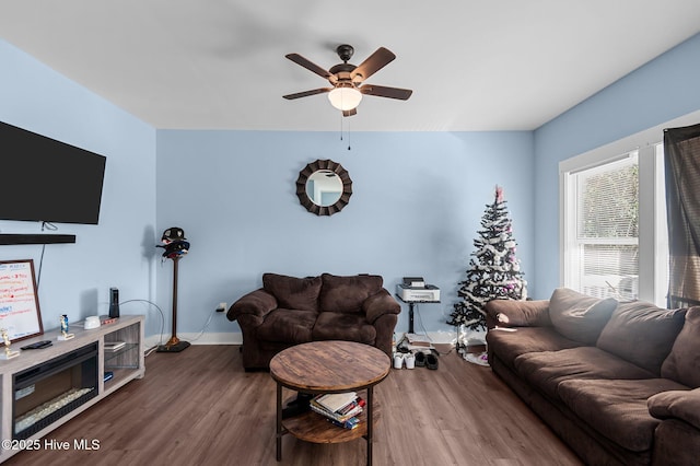 living room featuring baseboards, a ceiling fan, and wood finished floors