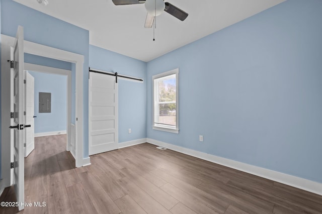 105 Bryan Pl, Washington, NC 27889 - unfurnished bedroom featuring a barn door, wood finished floors, baseboards, electric panel, and a ceiling fan