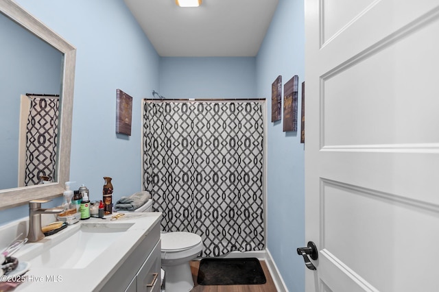 bathroom featuring toilet, vanity, a shower with curtain, and wood finished floors