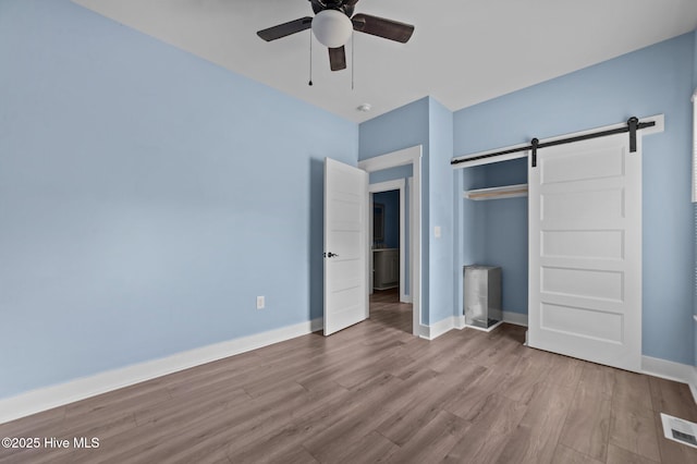105 Bryan Pl, Washington, NC 27889 - unfurnished bedroom with a barn door, wood finished floors, a closet, and baseboards