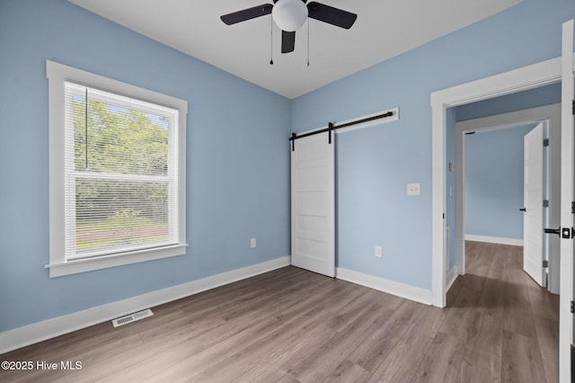 105 Bryan Pl, Washington, NC 27889 - unfurnished bedroom with wood finished floors, a barn door, baseboards, and a ceiling fan