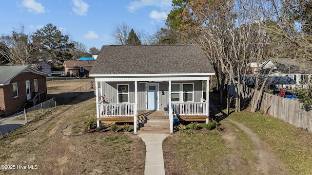 bungalow-style house featuring roof with shingles, a porch, a front lawn, and fence