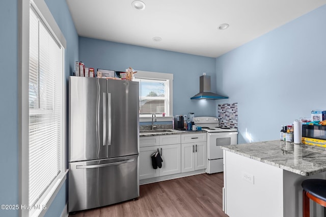 kitchen with freestanding refrigerator, white range with electric stovetop, white cabinets, wall chimney exhaust hood, and a sink