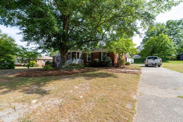 ranch-style home featuring covered porch, brick siding, and driveway