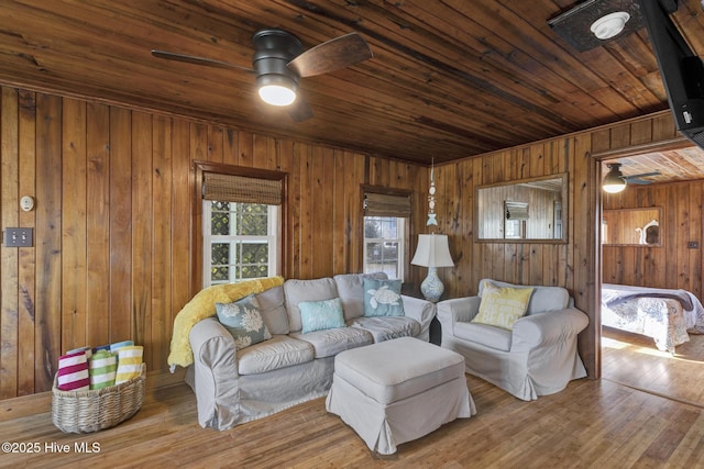 living room featuring ceiling fan, wood finished floors, wood ceiling, and wooden walls