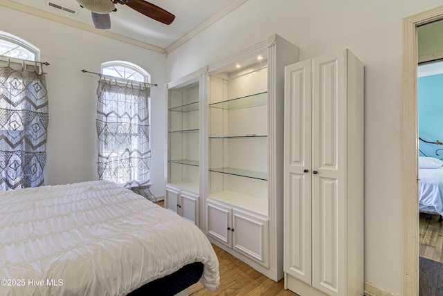 bedroom featuring a ceiling fan, light wood-type flooring, visible vents, and crown molding