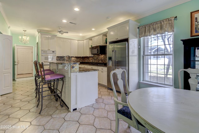 kitchen with appliances with stainless steel finishes, white cabinets, and decorative light fixtures