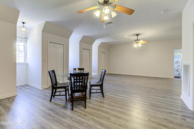 dining room featuring light wood-type flooring, baseboards, visible vents, and ceiling fan with notable chandelier