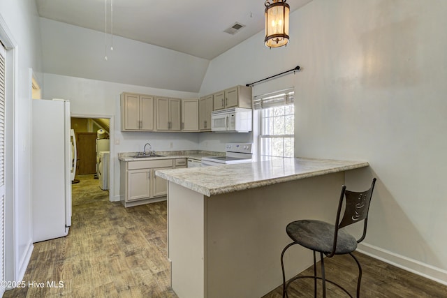 kitchen featuring a sink, a peninsula, white appliances, and hanging light fixtures