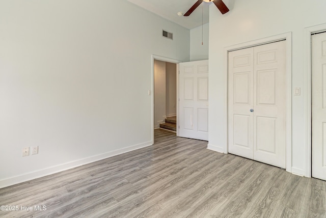 unfurnished bedroom featuring high vaulted ceiling, a ceiling fan, visible vents, baseboards, and light wood finished floors