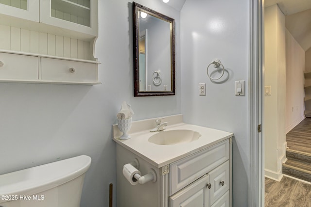 bathroom with baseboards, vanity, toilet, and wood finished floors