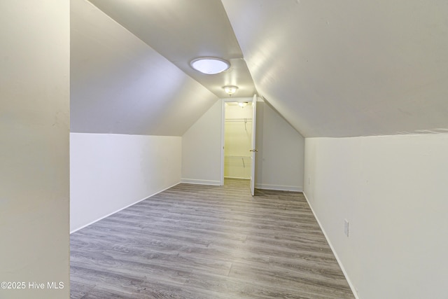 bonus room with lofted ceiling, baseboards, and light wood finished floors